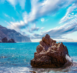 Rock formation on sea shore against sky