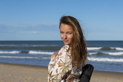 Woman walking alone on the sandy beach at sunset