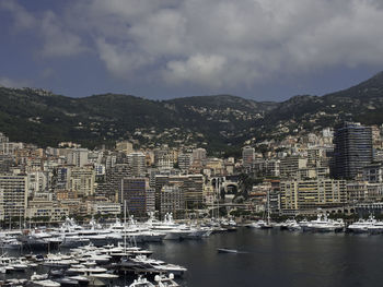 Sailboats moored in harbor against buildings in city