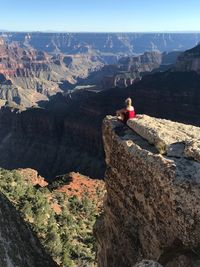 Man sitting on rock by mountain