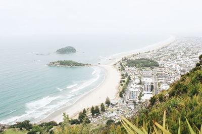 High angle view of city by sea against sky