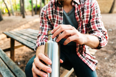 Midsection of man holding bottle outdoors