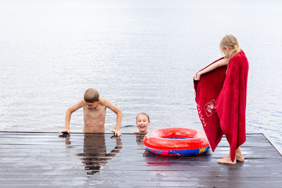 Full length of siblings on water