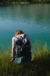 Rear view of woman walking by plants against lake