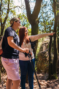 Woman pointing out the view from the top of the mountain to her friend. tourists hiking in nature. 