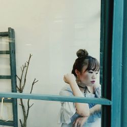 Thoughtful young woman seen through glass window