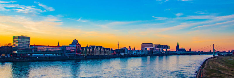 Bridge over river and buildings against sky during sunset