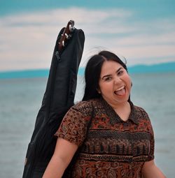 Portrait of a smiling young woman against sea