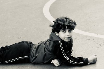 Portrait of boy lying on road