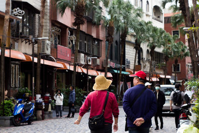 Rear view of people walking on street amidst buildings