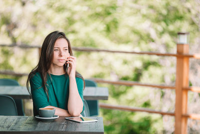 Young woman drinking coffee while sitting on table