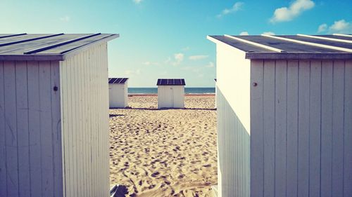 Beach huts at beach against blue sky