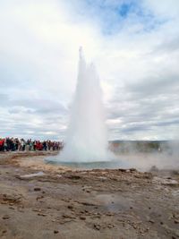 View of waterfall against cloudy sky