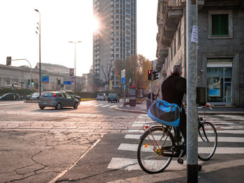 Man riding bicycle on city street against buildings