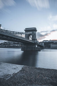 Bridge over river against cloudy sky