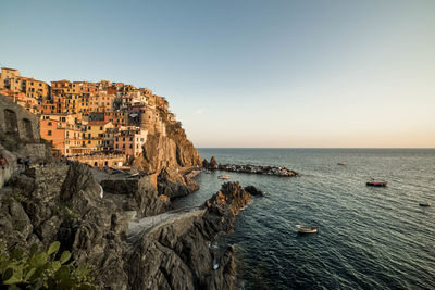 Houses on rock formation at manarola by sea against clear sky