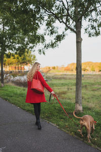 Woman with dog on road against trees