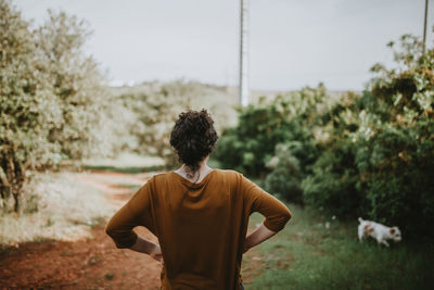 Rear view of man standing on field against sky