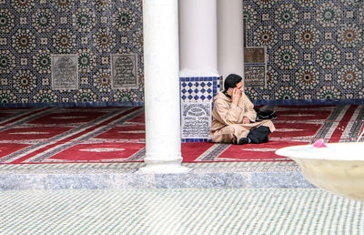 Full length of man sitting on mobile phone