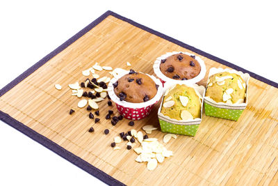 High angle view of sliced dried fruits by muffins on carpet against white background