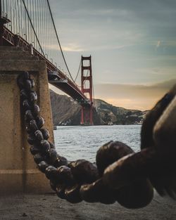 Close-up of golden gate bridge against sky during sunset