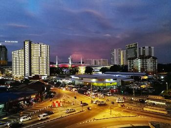 High angle view of illuminated street amidst buildings in city at night