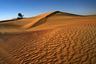 Sand dunes in desert against clear blue sky