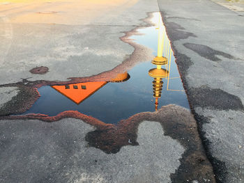 High angle view of reflection in puddle on street during sunset