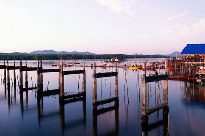 Wooden posts in lake against sky