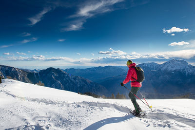 Man skiing on snowcapped mountains against sky
