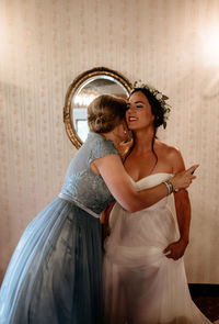 Maid of honor hugging a happy bride before wedding ceremony