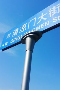 Low angle view of sign board against blue sky