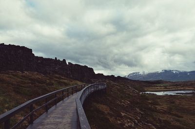 Scenic view of road by mountains against sky