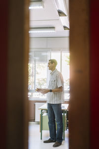 Professor teaching in classroom seen through doorway