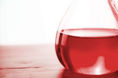 Close-up of red drink in container on table against white background