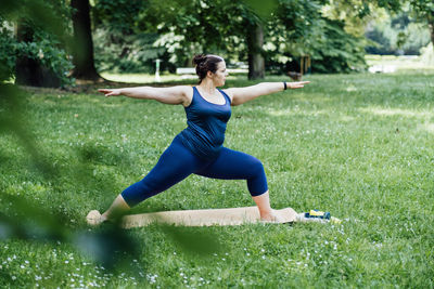 Happy confident smiling plus size curvy woman doing yoga stretching pilates workout, exercising