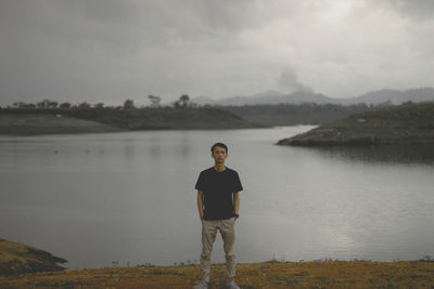 Portrait of man standing on lake against sky