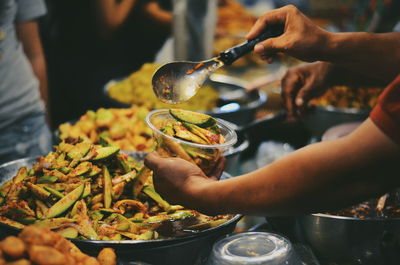 Cropped hands filling bowl with pickle in market