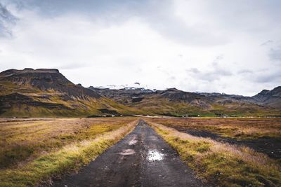 Road amidst field against sky