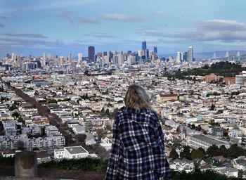 Rear view of woman standing by cityscape against sky