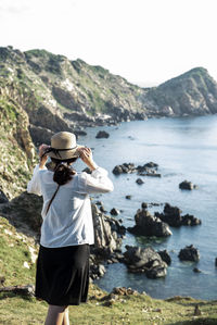 Rear view of woman standing at beach against sky - eo gio - wind strait