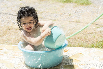 Happy girl playing in bucket with water