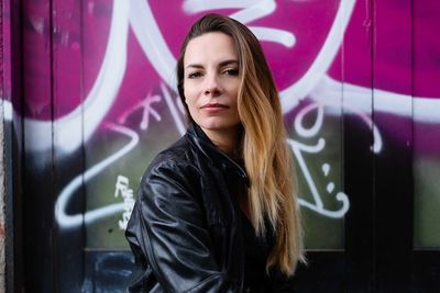 Portrait of young woman standing against wall