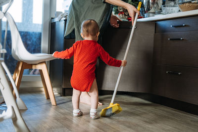 Little mothers helper. cute toddler baby girl with mop help her mom do housework in kitchen. 