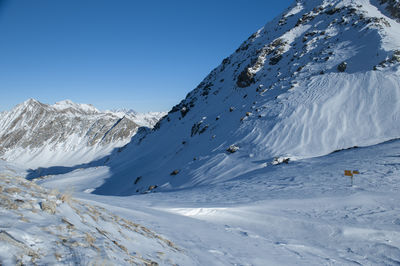 Scenic view of snow covered mountains against clear blue sky