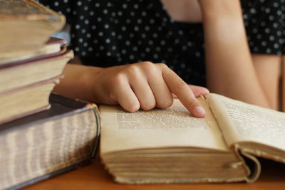 Midsection of woman reading book on table