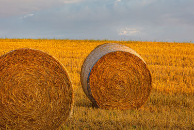 Hay bales on field against sky