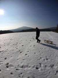 Man standing on snow covered landscape against sky