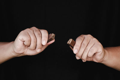 Close-up of hand holding hands over black background
