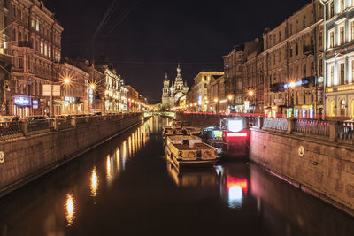 Canal amidst illuminated buildings in city at night